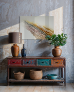 Serenity 2 hung above an eclectic wooden console with a table lamp, potted plant and woven baskets