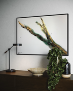 Rooted 1 on a pale wall above a dark console with a lamp, plant and bowl