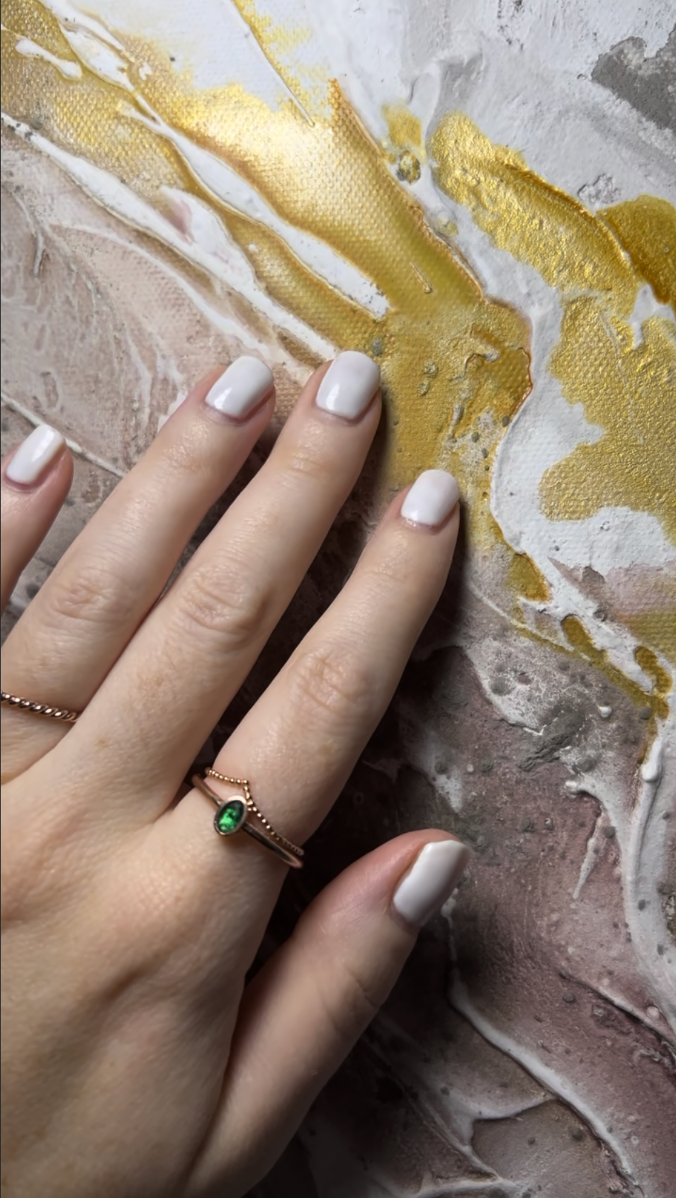 A hand resting on the textured gold and white surface of Liberation 1, art meant to be touched