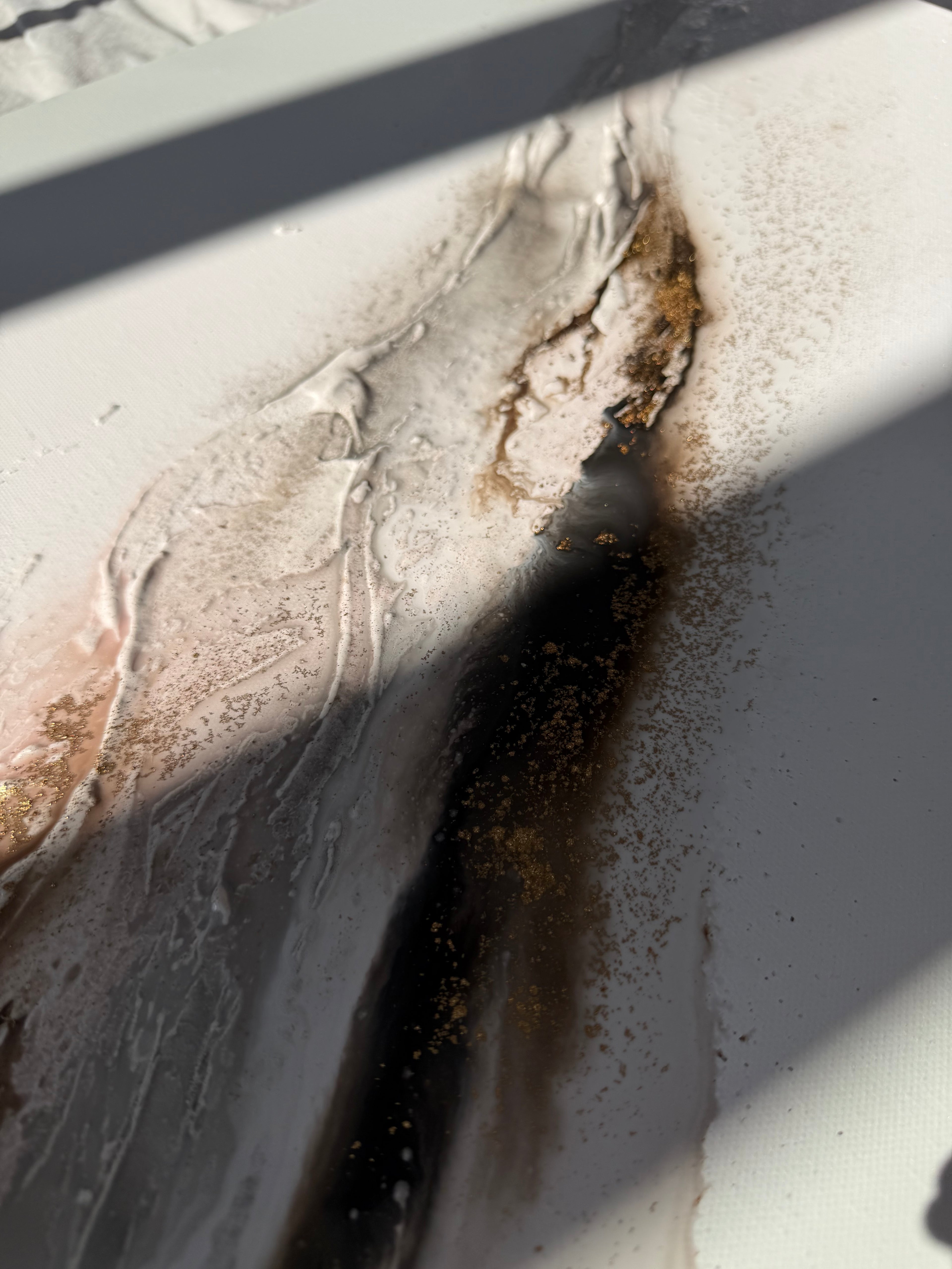 Close-up of Bedrock in raking light, coarse sand and gold pigment over brown and cream.