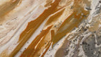 Video close-up of gold pigment moving over the textured surface of Serenity 2